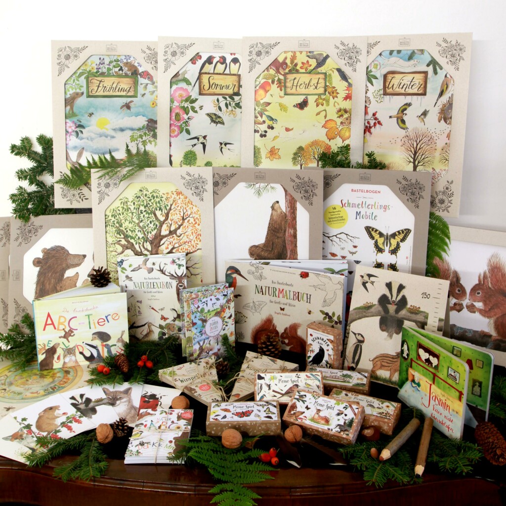 Spiele, Bilderbücher, Poster und Papeteriewaren. Prsäsentiert auf einem Holztisch mit Naturmaterialien dekoriert