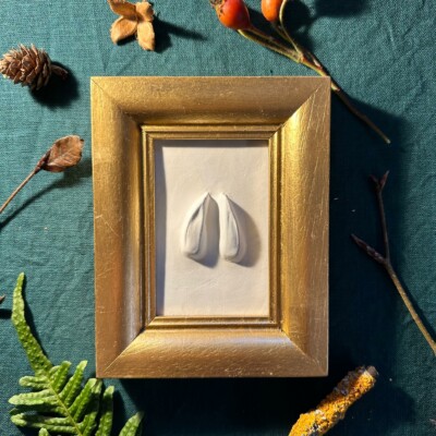 Gipsabguss einer Rehspur gerahmt in einem eckigen Goldrahmen aus Holz