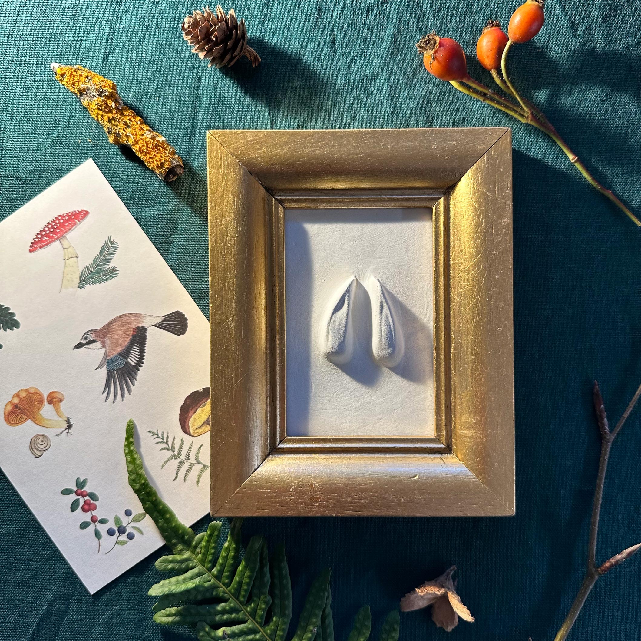 Gipsabguss einer Rehspur gerahmt in einem Goldrahmen aus Holz