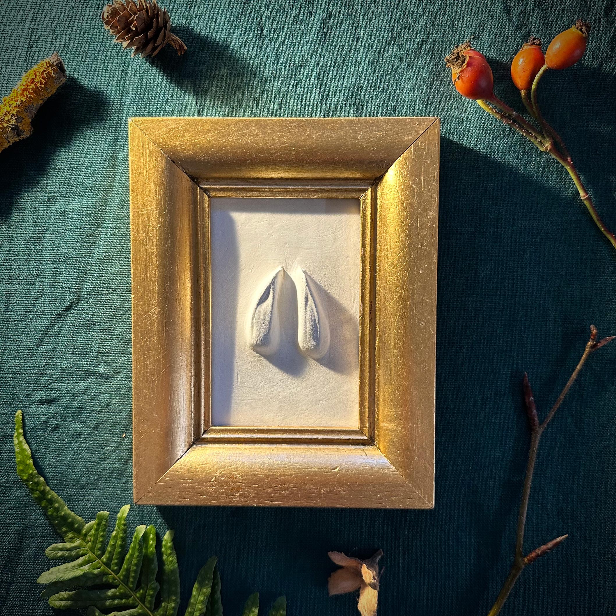 xGipsabguss einer Rehspur gerahmt in einem Goldrahmen aus Holz