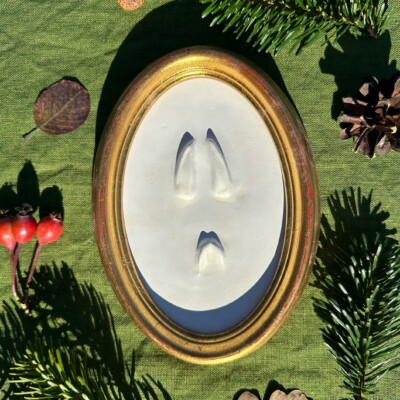 Gipsabguss einer Rehspur und Rehkitz gerahmt in einem ovalen Goldrahmen