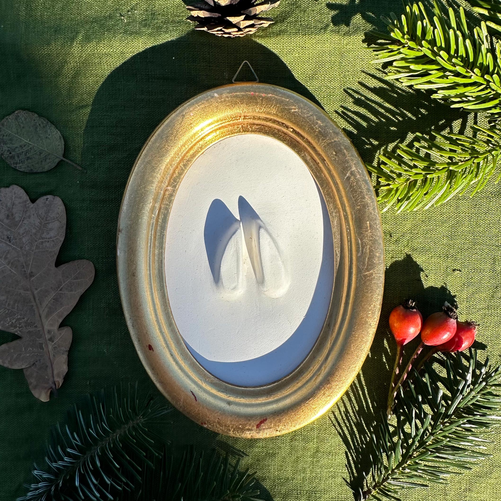 Gipsabguss einer Rehspur gerahmt in einem ovalen Goldrahmen aus Holz