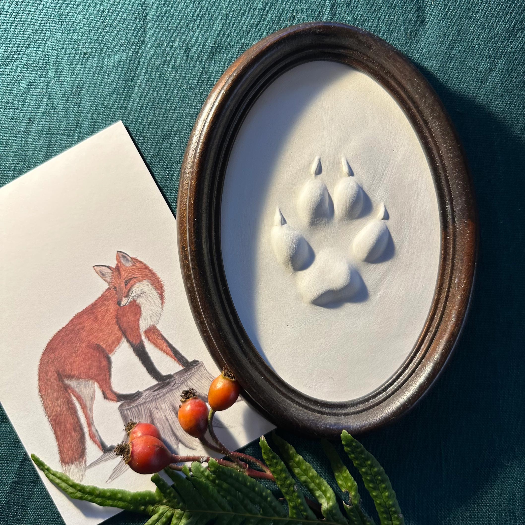 Gipsabguss einer Fuchsspur gerahmt in einem ovalen Rahmen aus Holz